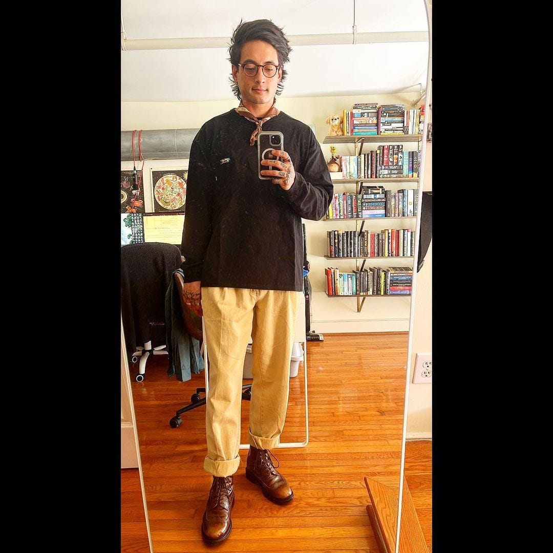 stylish man wearing a black shirt with a bandana around his neck and pleated pants