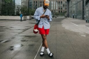 stylish man wearing a blue oxford shirt with red shorts and two-tone loafers
