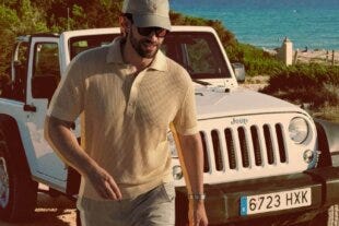 stylish man wearing a butter yellow knit polo shirt walking away from a white jeep
