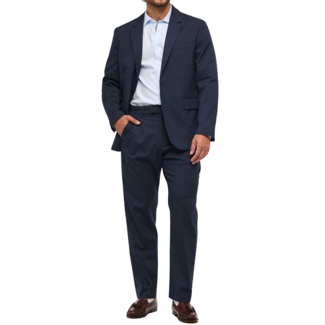 man with an athletic build wearing a navy suit with a white shirt and dark shoes