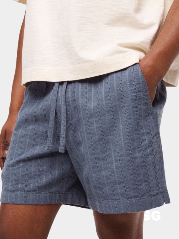 close-up of a man wearing a white t-shirt and blue textured drawstring shorts