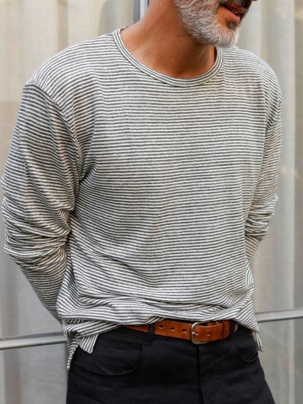 close-up of a man wearing a striped long-sleeve linen tee with a brown leather belt and black pants