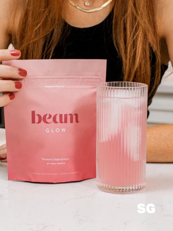 beam "glow" supplement powder in pouch and shown mixed into glass of water