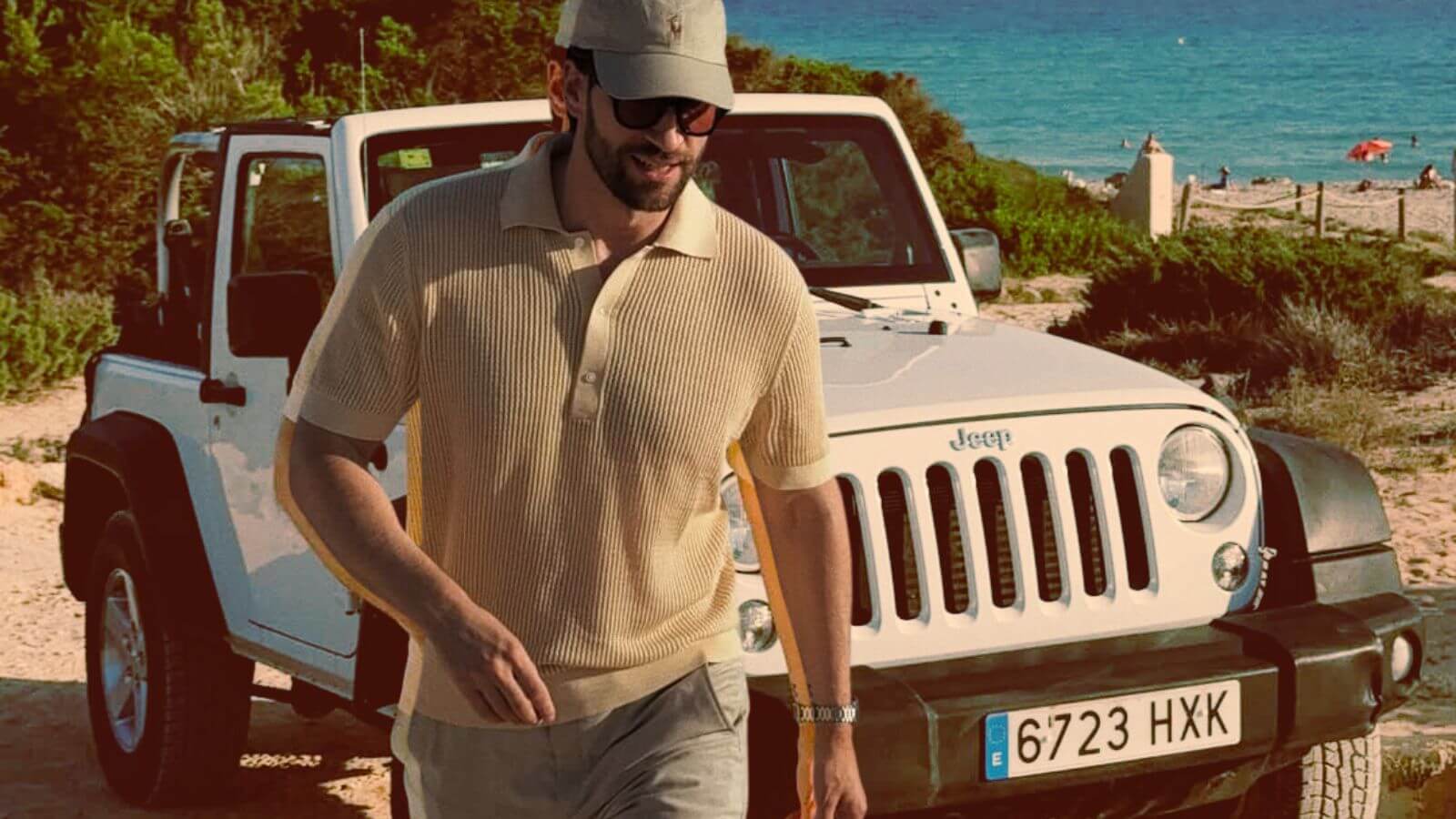 stylish man wearing a butter yellow knit polo shirt walking away from a white jeep