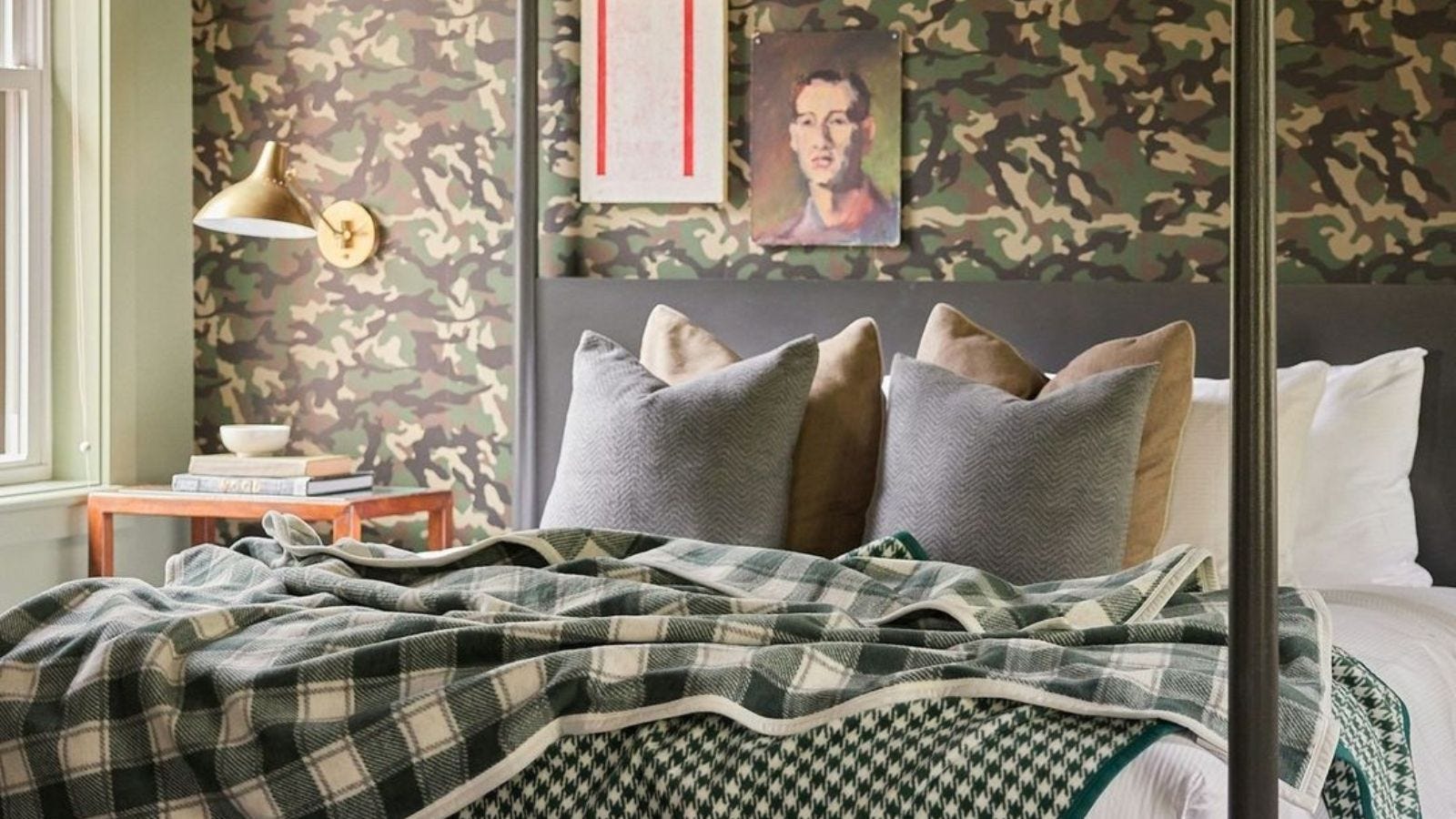 two patterned green throw blankets laid out on a 4-poster bed in a bedroom with green camo wallpaper
