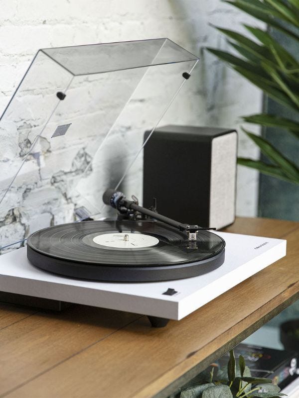 stylish record player set on a console table against a whitewash brick wall