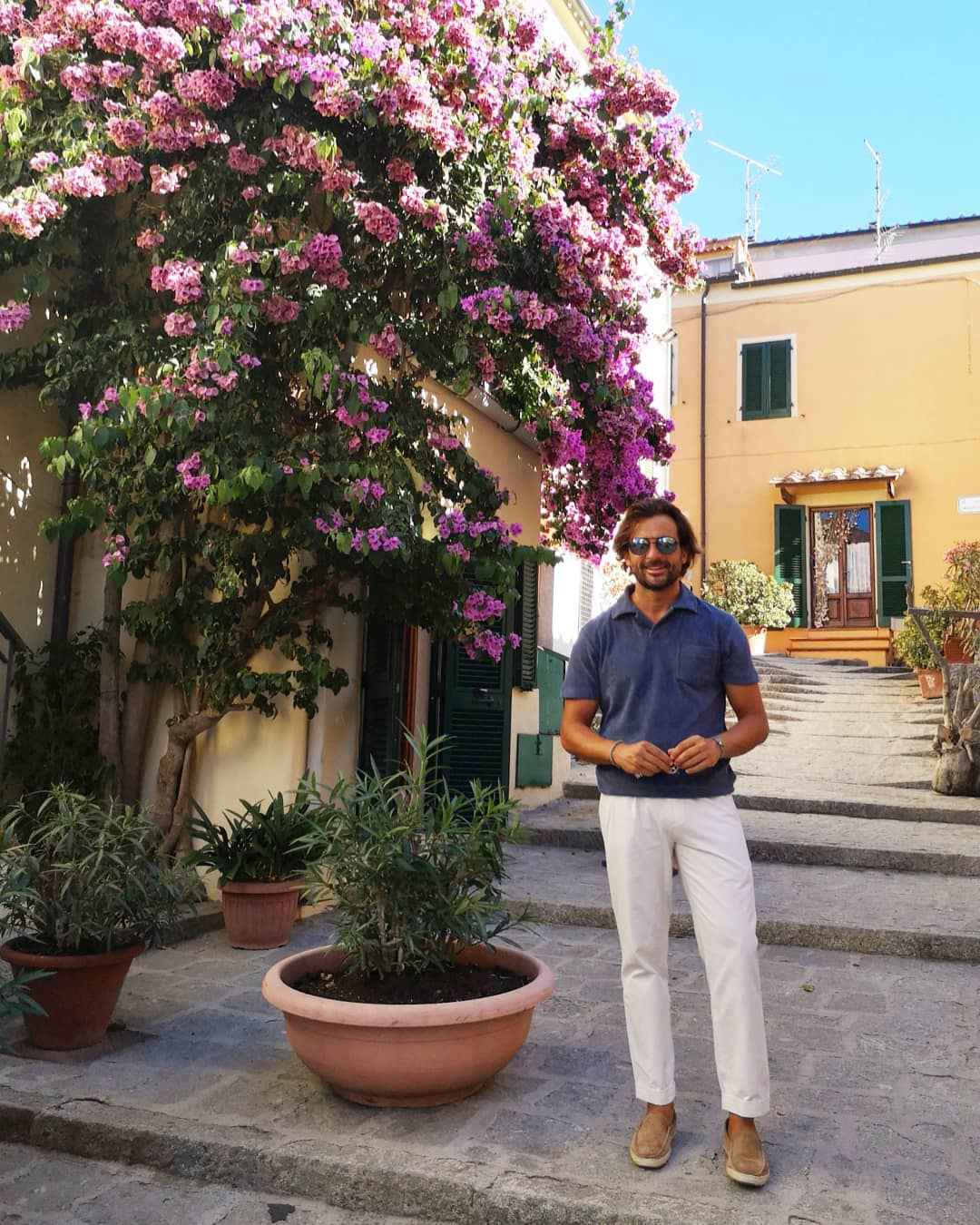 stylish man wearing a navy polo with white pants and suede loafers