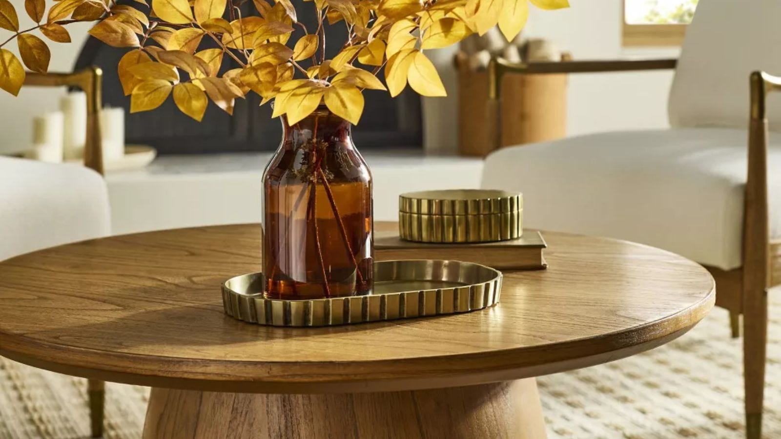 vase with yellow leaves on a brass decorative tray sitting on a coffee table