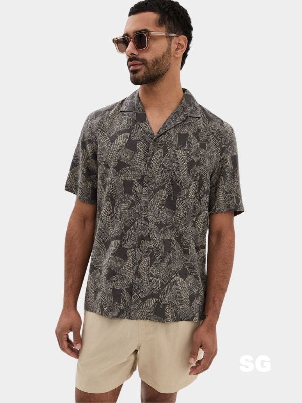 close-up of a stylish man wearing a patterned camp shirt and khaki shorts
