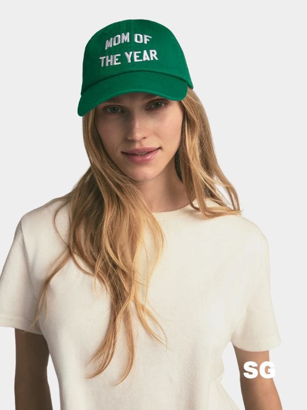 stylish blonde woman wearing green baseball hat that reads "mom of the year"