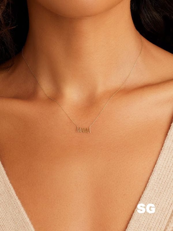 close-up of a woman wearing a gold necklace that reads "mama"