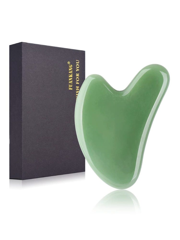 a green gua sha tool next to a black rectangular container for the tool