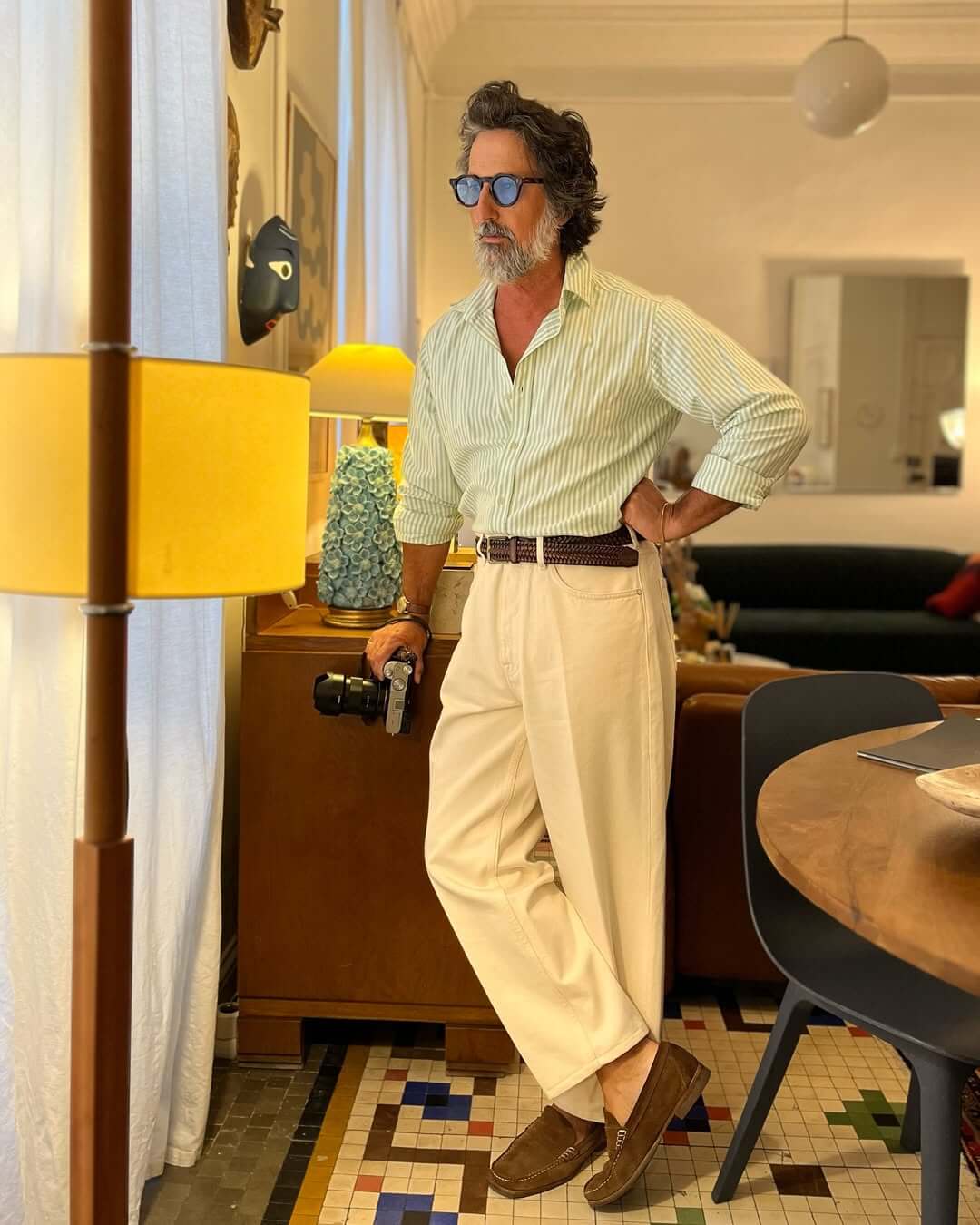 stylish older man wearing a green and white striped button down shirt, brown braided leather belt, and wide-leg white jeans