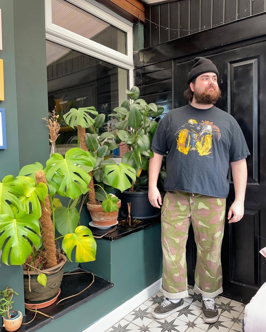 stylish man wearing a cropped graphic tee with camo pants and sneakers