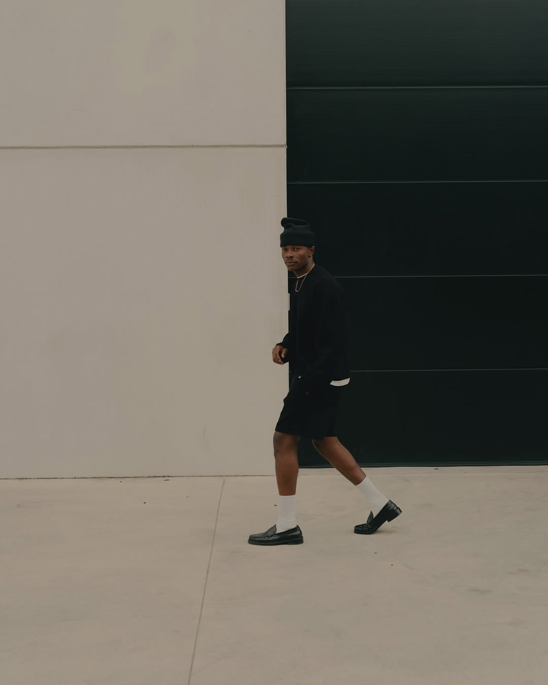 stylish man wearing black hybrid shorts with black loafers and tall white athletic socks