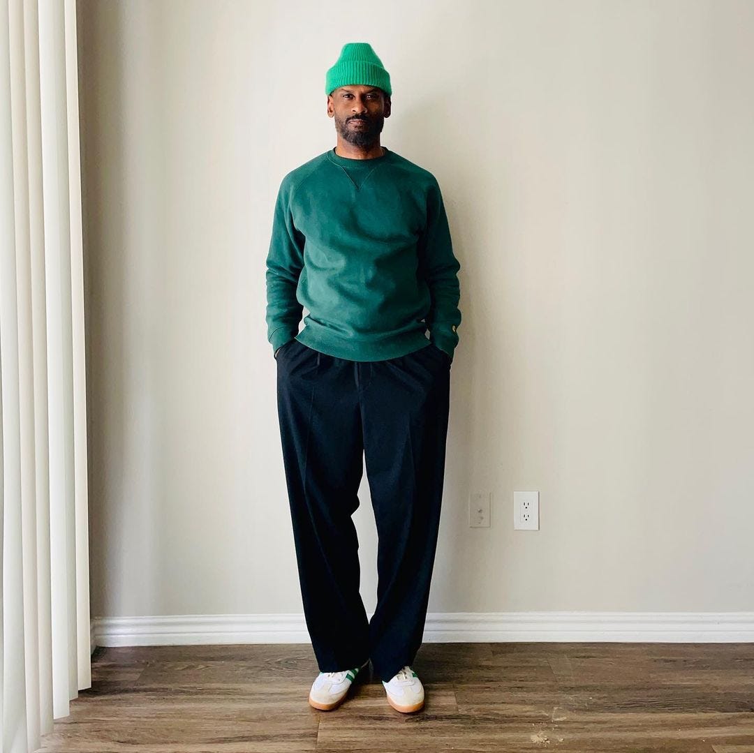 stylish man wearing a green sweater with dark pants and a green beanie