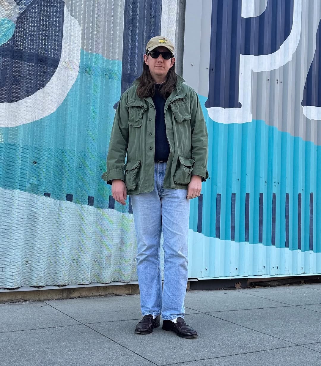 stylish man wearing a field jacket with light blue jeans