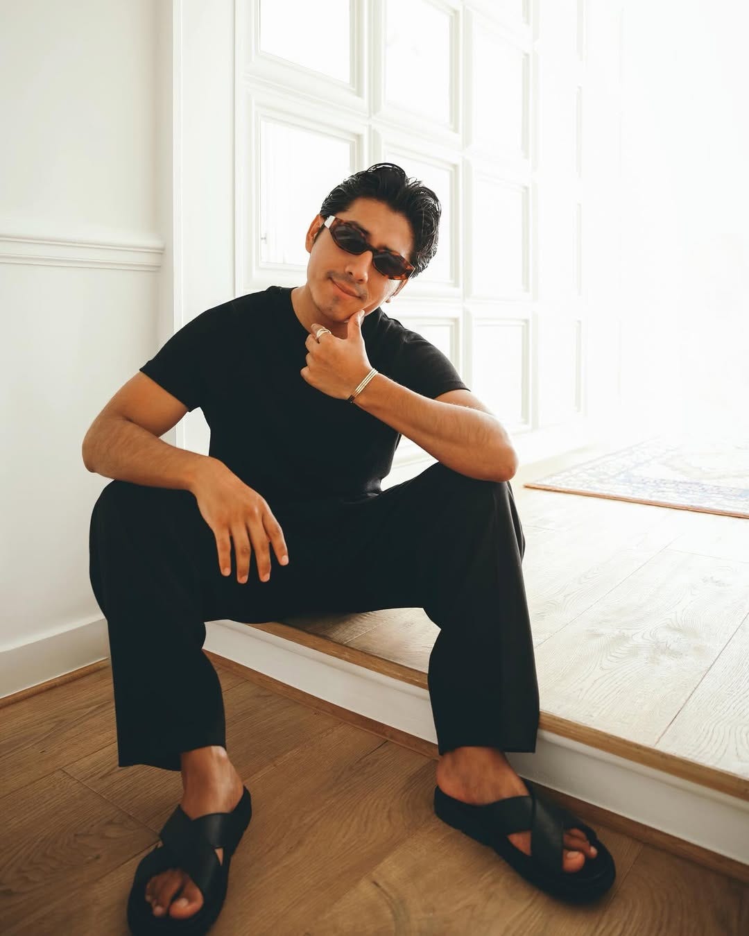 stylish man wearing a black t-shirt, black pants, and black leather sandals