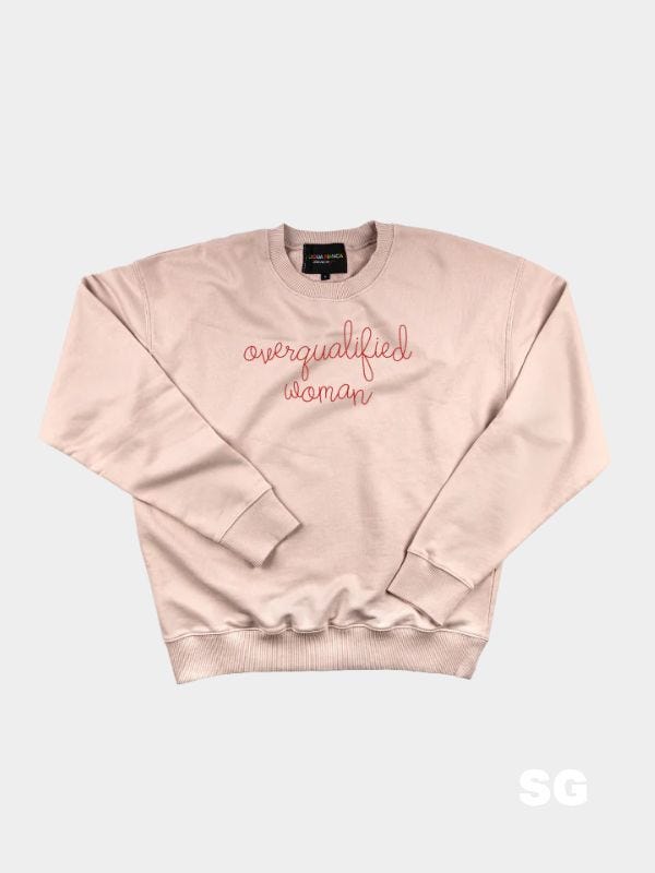 pink crewneck sweatshirt with "overqualified woman" embroidered across the chest