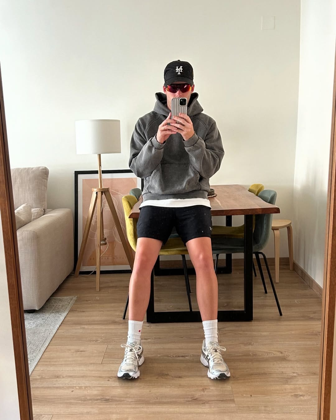 stylish man wearing black hybrid shorts with a grey hoodie and asics sneakers