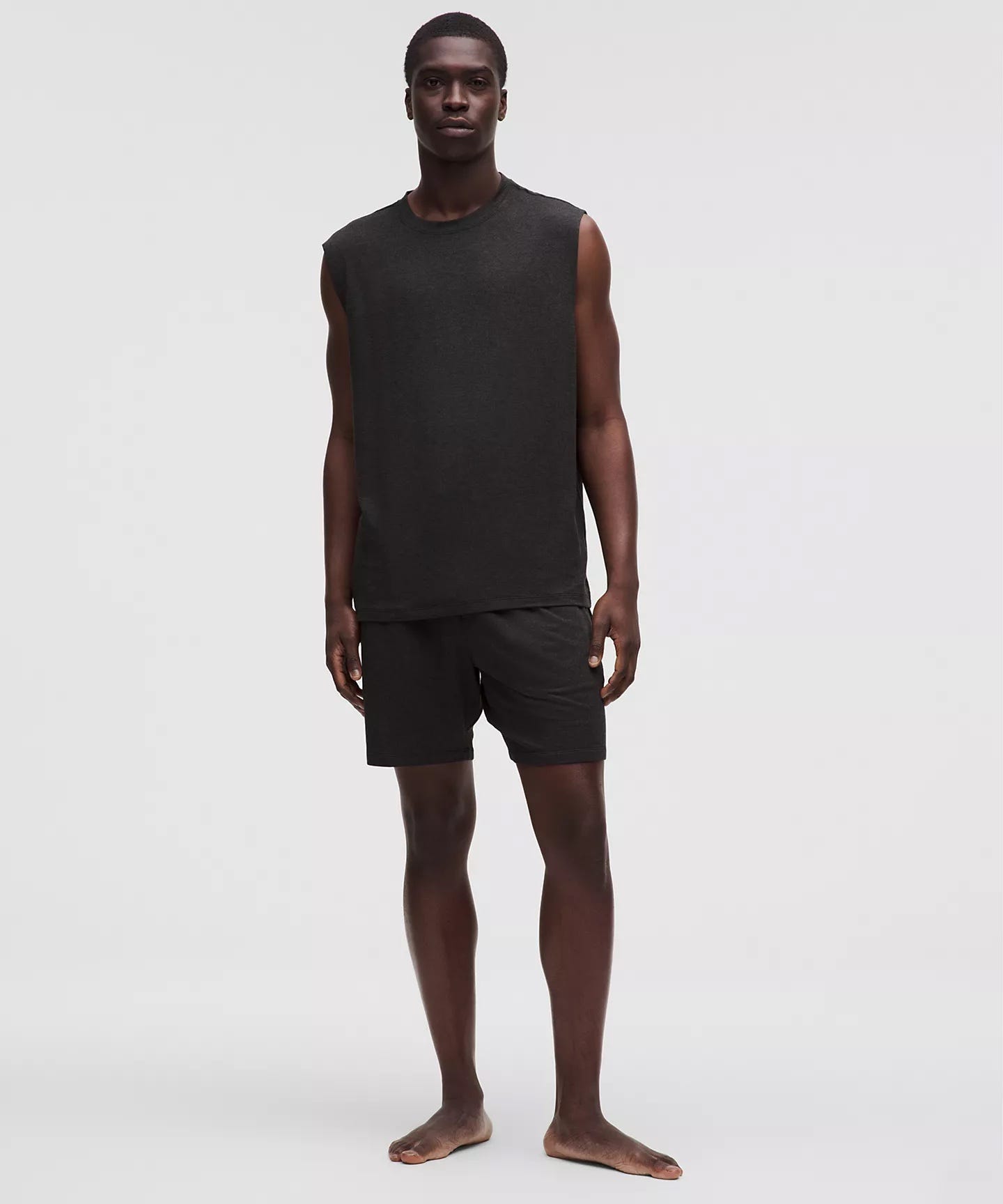 man wearing a stylish yoga class outfit of a sleeveless black tank and black shorts, included in a roundup of men's gym style women want to see guys wearing