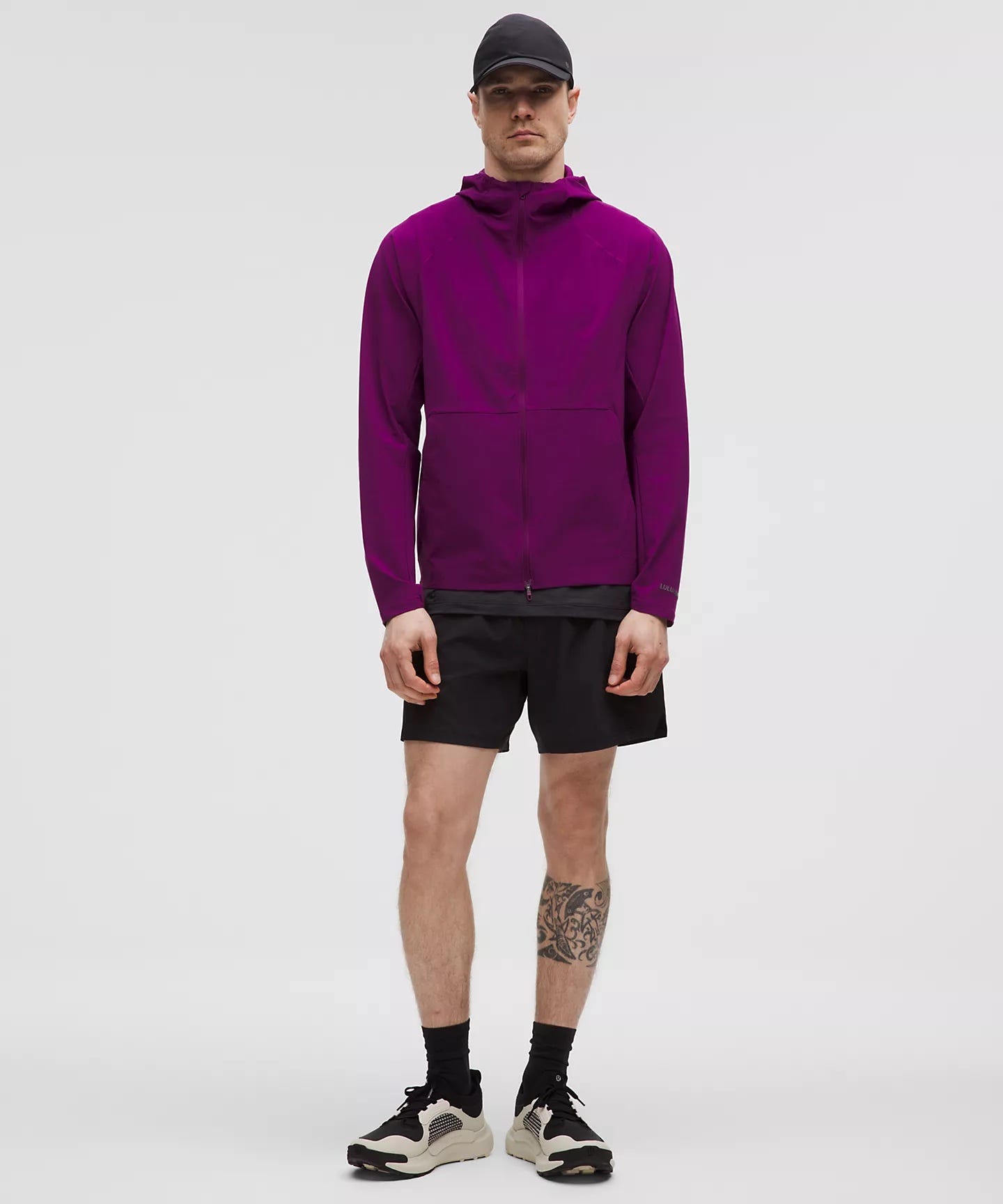 stylish man in a purple shell jacket with black shorts, black athletic socks, and black sneakers, included in an article of men's gym style women want to see guys wearing