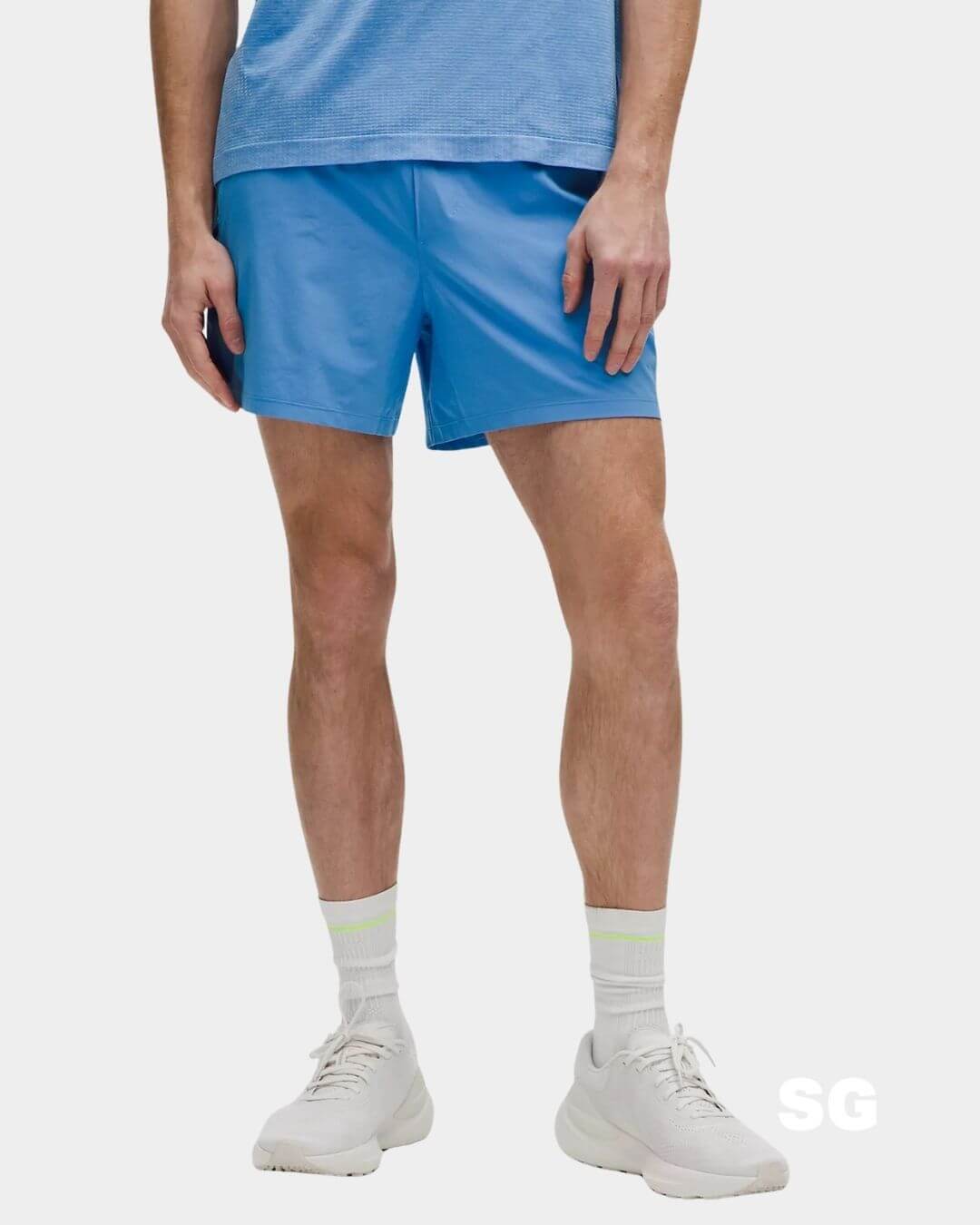 man from the waist down wearing blue athletic shorts and white sneakers