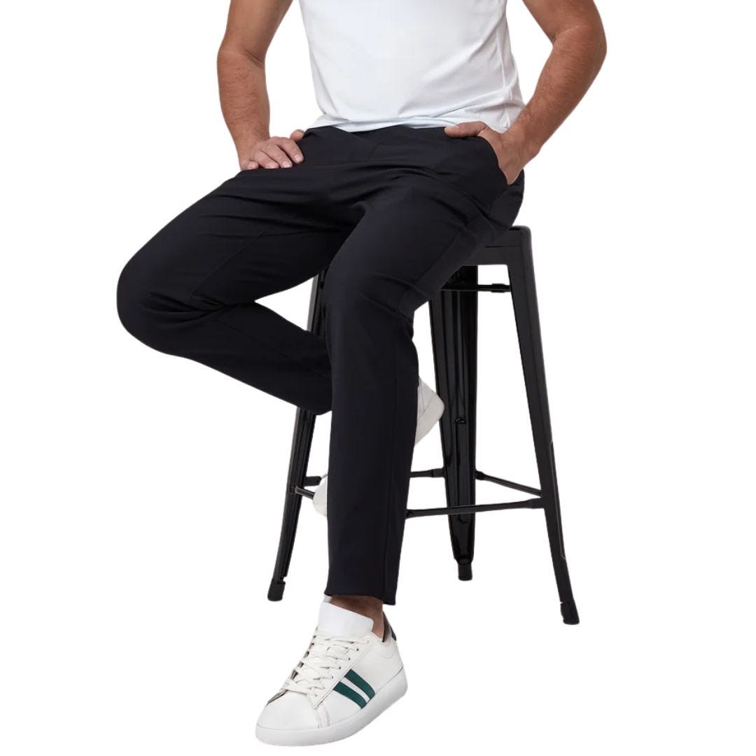man from the waist down, sitting on a stool, wearing black pants and a white t-shirt