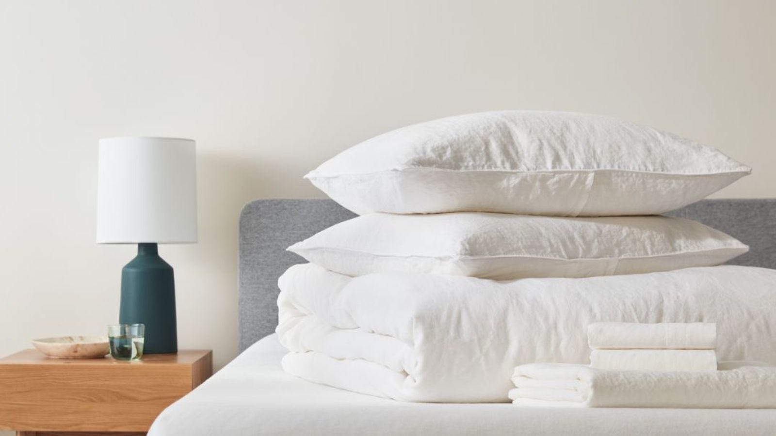 clean bed with folded sheets, duvet, and pillows sitting on top