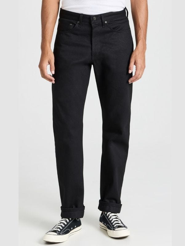 man from the waist down wearing black jeans and black converse sneakers