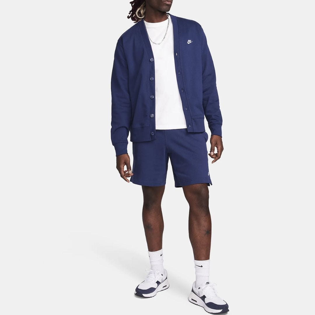 torso of man wearing deep purple cardigan, open over a white t-shirt, with coordinating deep purple shorts, tall socks and golf shoes