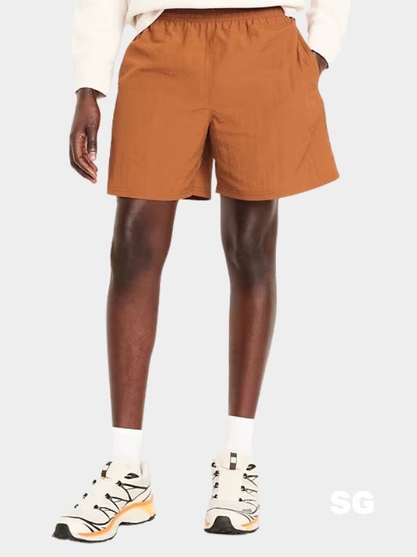 man wearing orange hybrid shorts and off-white sneakers