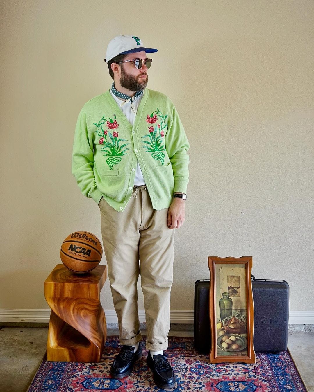 stylish man wearing an embroidered green cardigan with chinos and a baseball hat