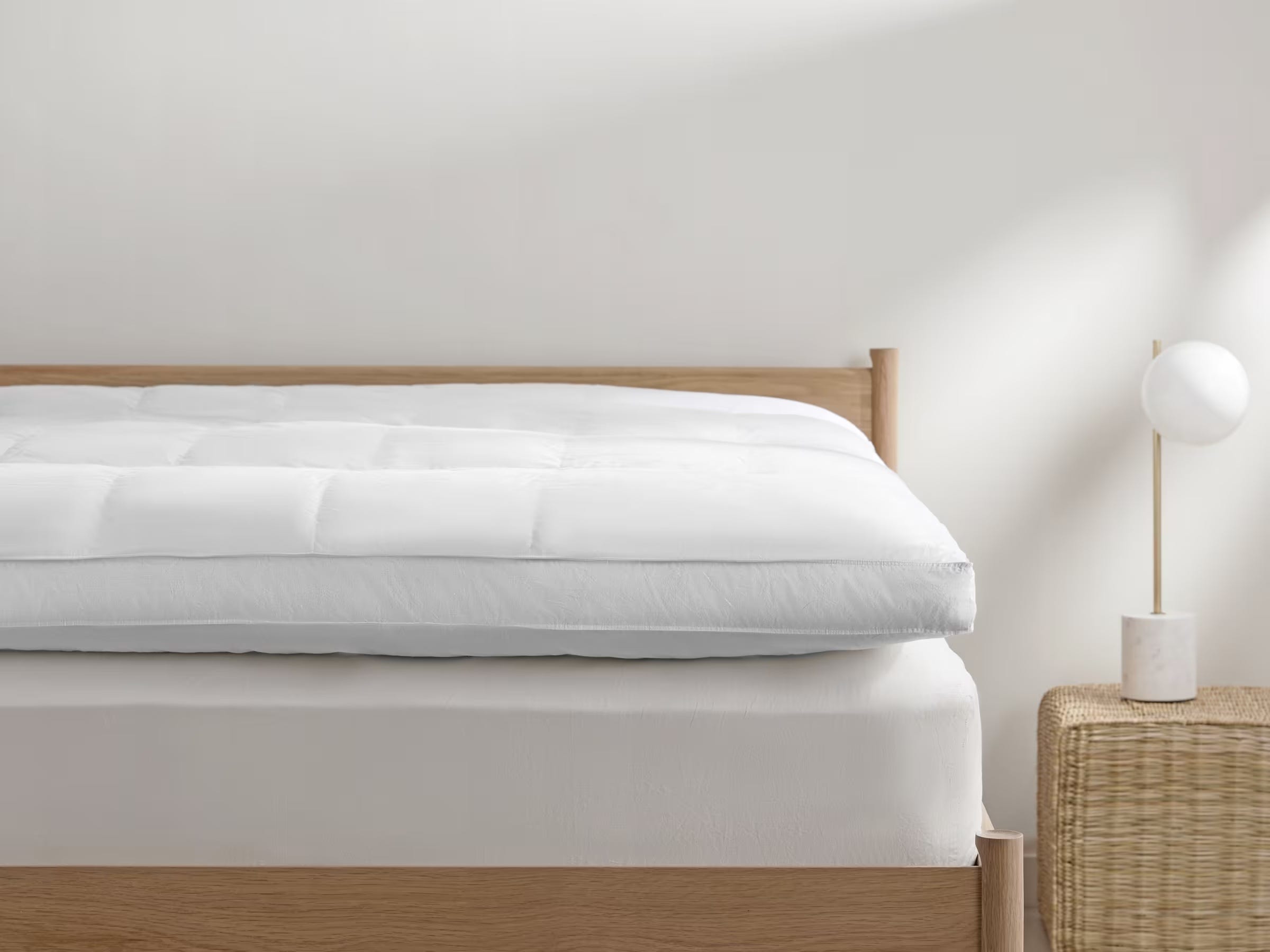 Down Mattress Topper on a white mattress set on a light wood bedframe