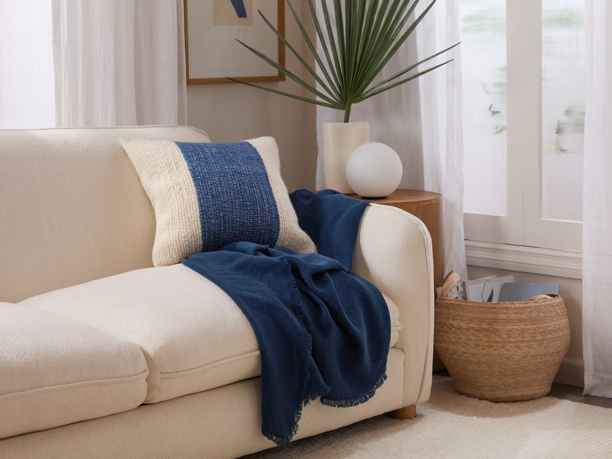 coastal living room with off-white coach and a blue throw blanket in front of a green plant on the side table