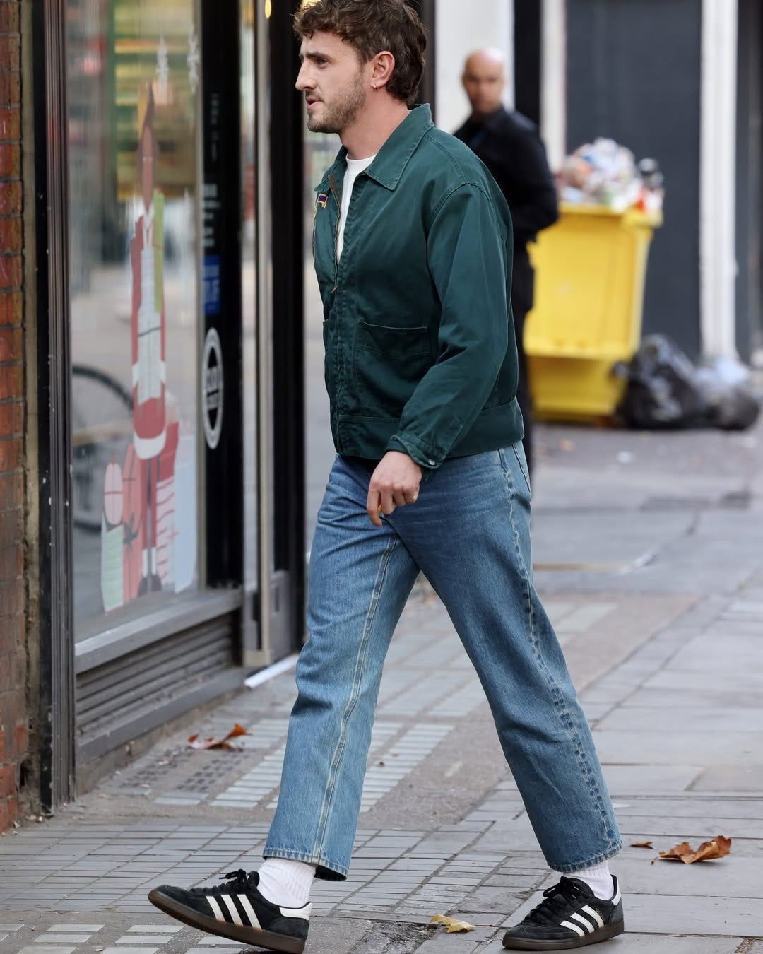 actor Paul Mescal wearing a green jacket over a white t-shirt with jeans and Adidas sneakers
