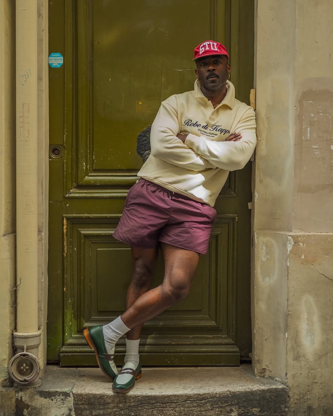 stylish man wearing a quarter zip sweatshirt with maroon shorts and loafers with socks
