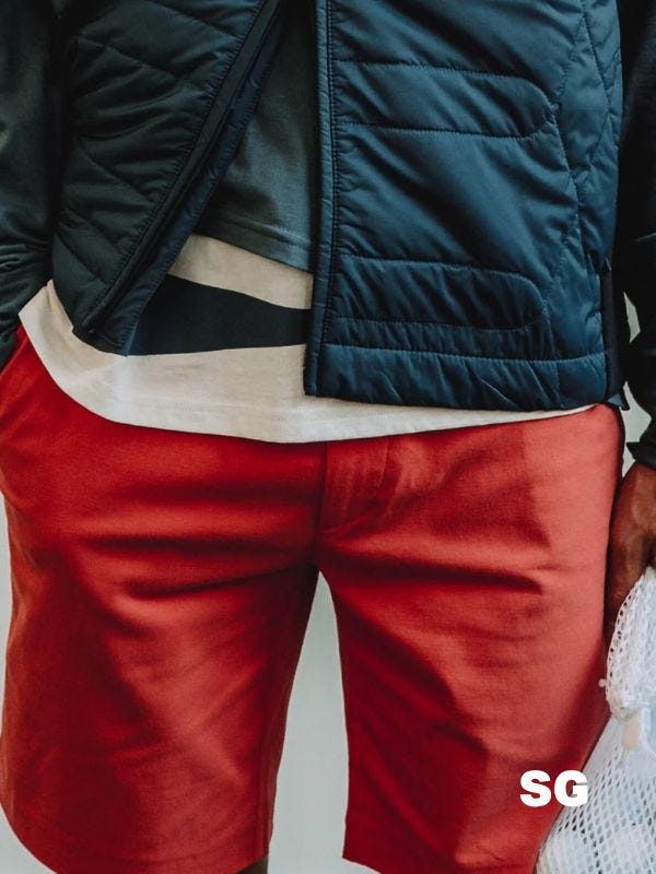 close-up of a stylish man wearing red shorts with a navy performance jacket