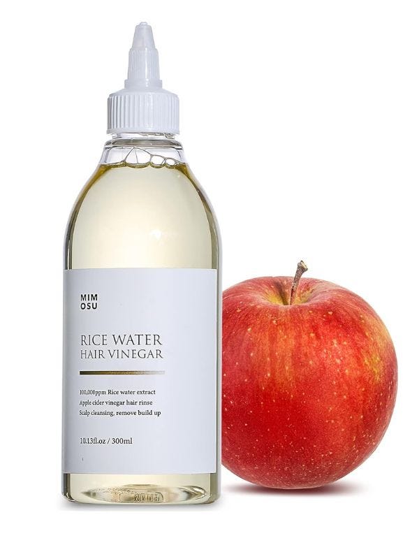 bottle of rice water hair vinegar next to an apple