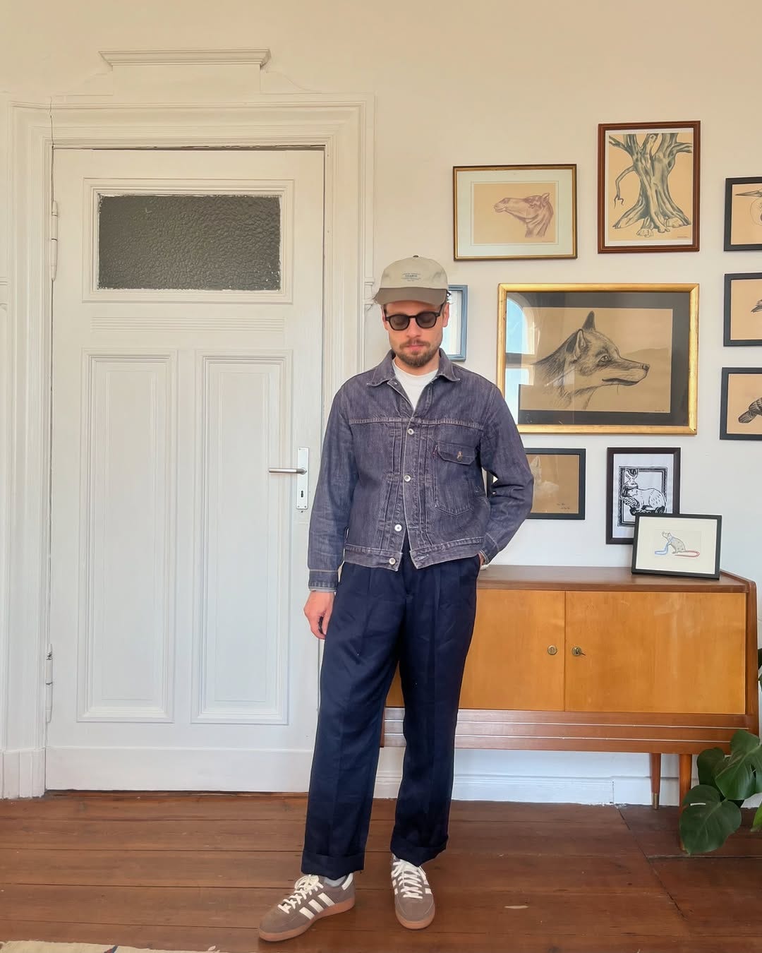 stylish man wearing brown Adidas Samba sneakers with blue pants and a denim jacket buttoned up