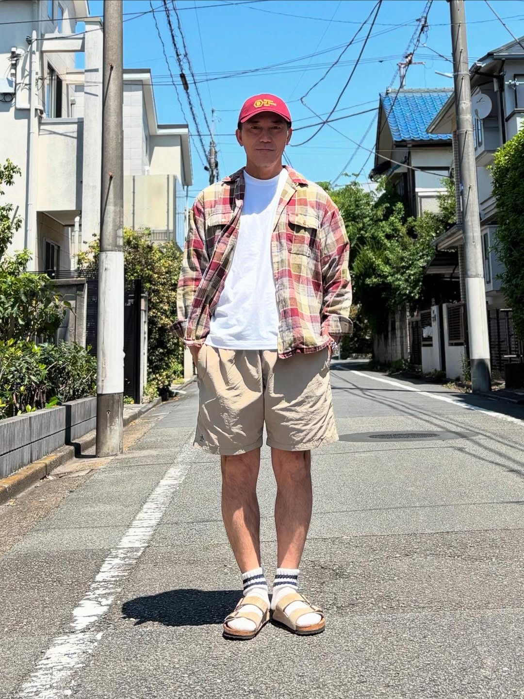 stylish man wearing a plaid long-sleeve shirt over a white t-shirt with khaki shorts and birkenstock sandals with socks
