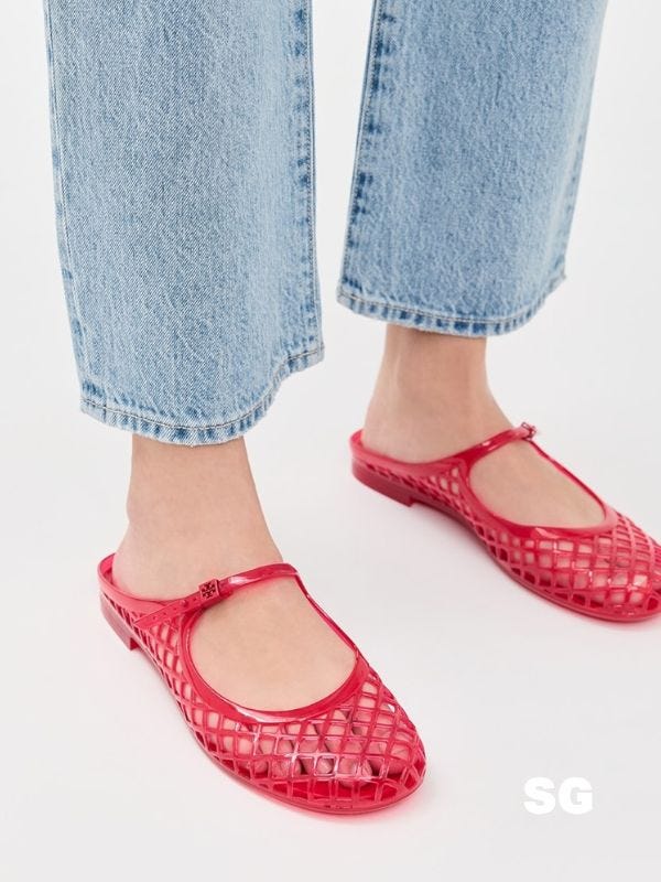 close-up of a woman wearing light jeans and red jelly flats