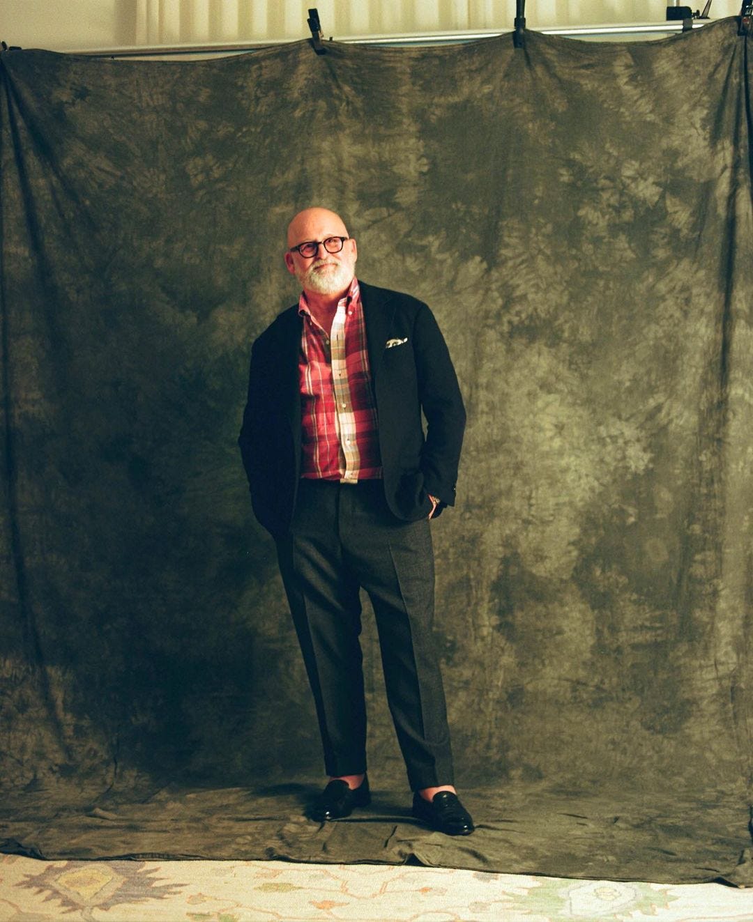 stylish older man wearing a dark blazer with a plaid shirt and dark trousers