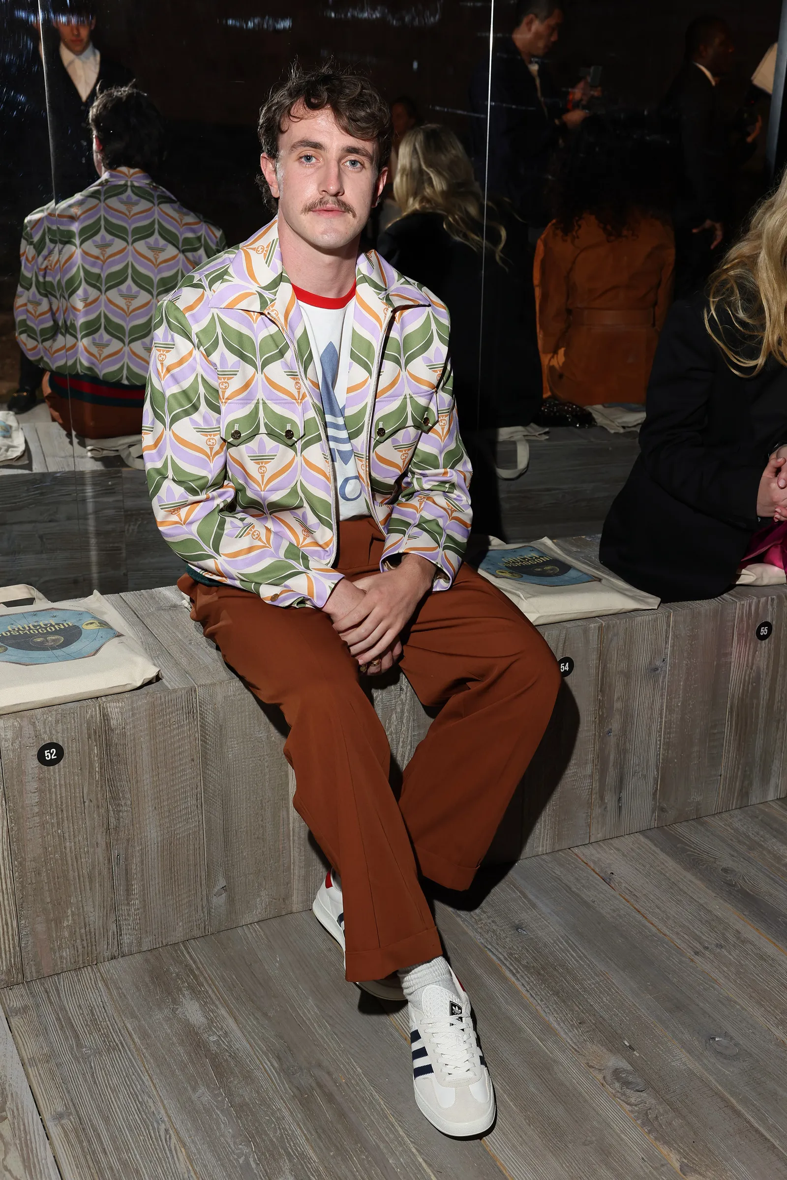 actor Paul Mescal wearing a patterned jacket over a vintage Adidas tee with brown pants and Adidas sneakers